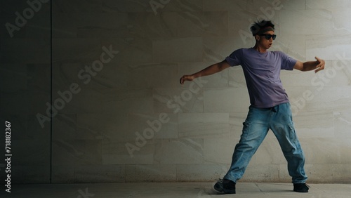 Skilled smart street dancer practice b-boy movement in building with gray background. Young handsome attractive choreographer perform energetic and active movement. Outdoor sport 2024. Sprightly.