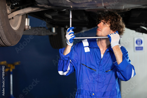 mechanic using ratchet wrench and fixing underneath the car