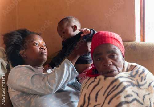 african refugee destitute family  bonding  together in the corner of a room, poverty, inside the house photo