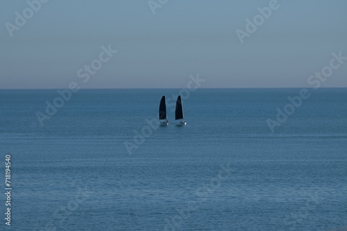 two boats floating in the middle of the calm sea