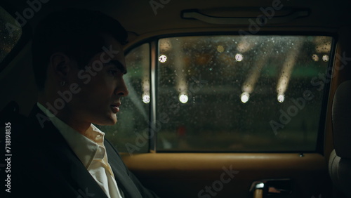 Stylish businessman commuting automobile night town closeup. Man looking window