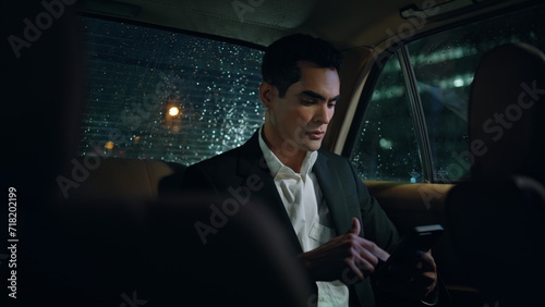 Serious man scrolling phone in evening auto close up. Businessman working at car © stockbusters