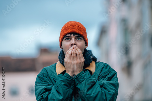 portrait of young man on the street in winter warm and wearing a hat