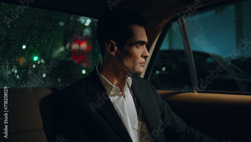 Handsome businessman looking car window at night closeup. Man travelling auto 
