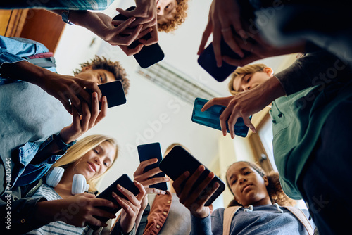 Below view of group of teenagers using smart phone at high school.