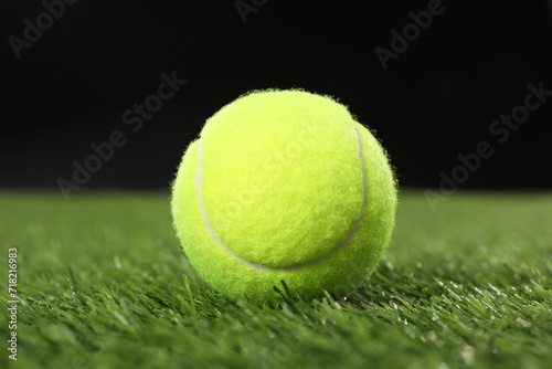 Tennis ball on green grass against black background, closeup © New Africa