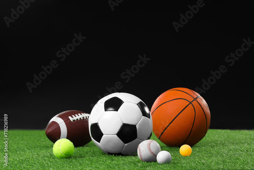 Many different sports balls on green grass against black background, space for text © New Africa