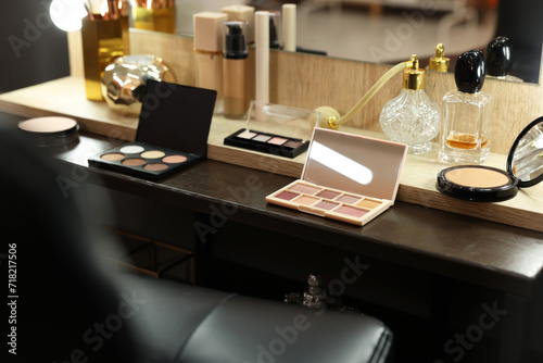 Makeup room. Cosmetic products and perfumes on wooden dressing table indoors © New Africa