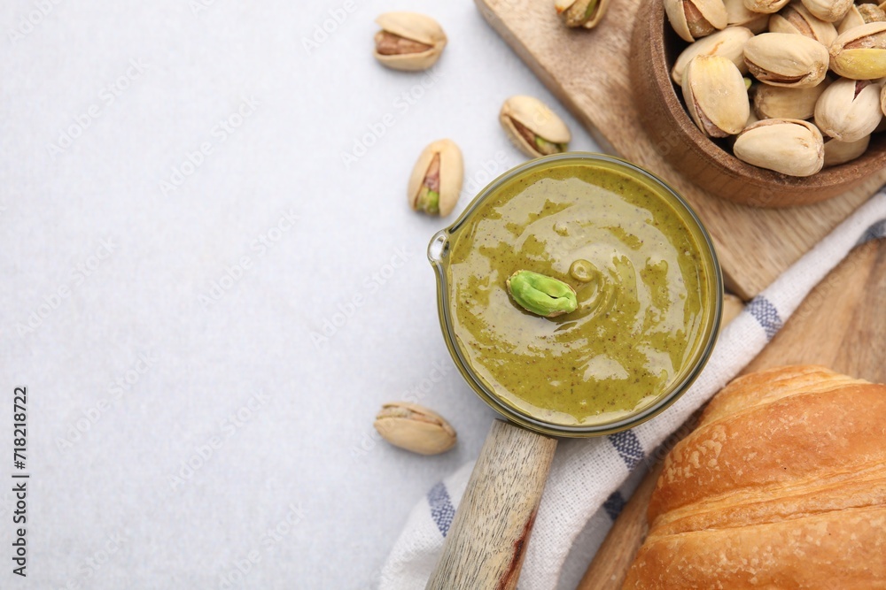 Tasty pistachio cream and nuts on light table, flat lay. Space for text Tasty pistachio cream and nuts on light table, flat lay. Space for text