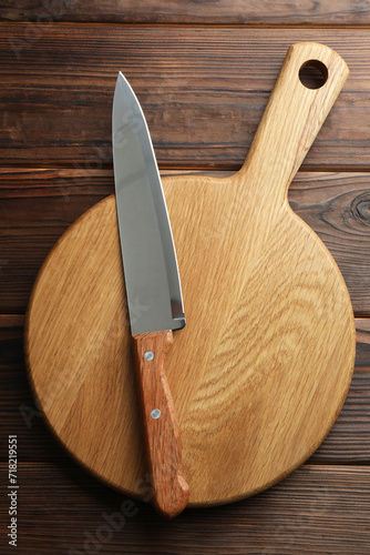Knife and board on wooden table, top view
