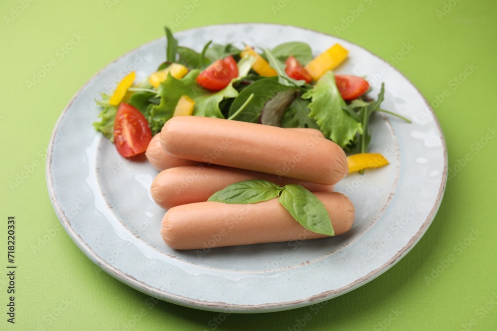 Delicious boiled sausages with salad on green