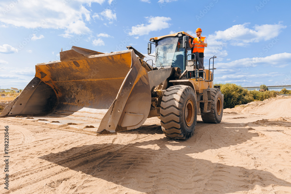 Driver of Excavator young man worker of sand industrial quarry. Construction site industry concept