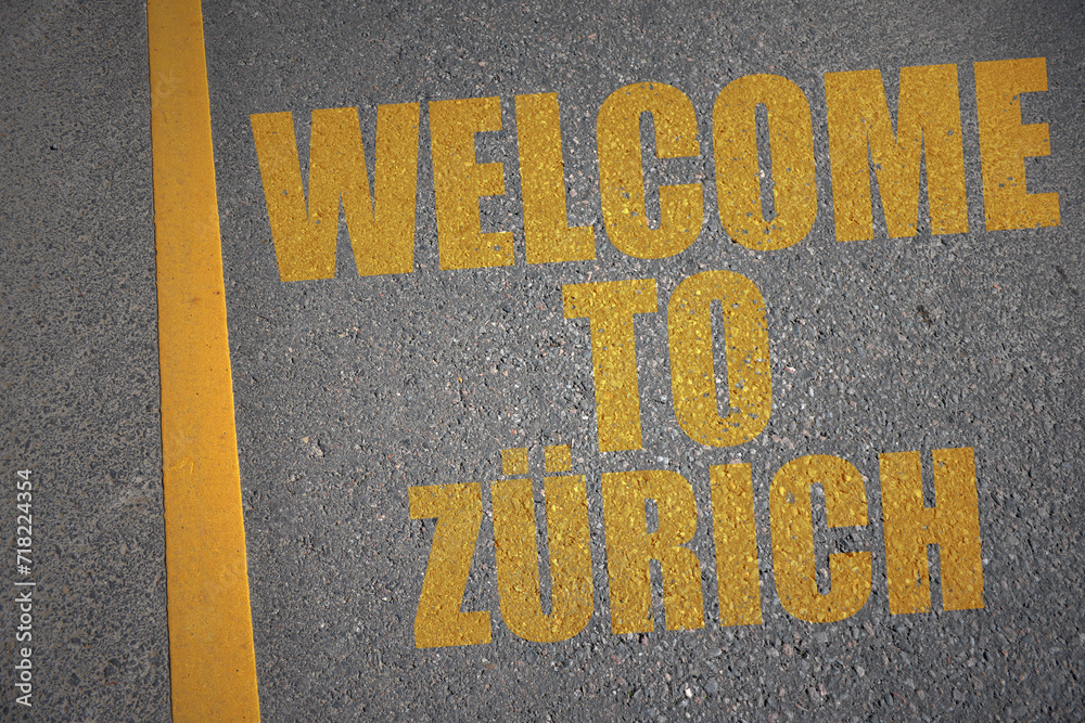 asphalt road with text welcome to Zurich near yellow line.