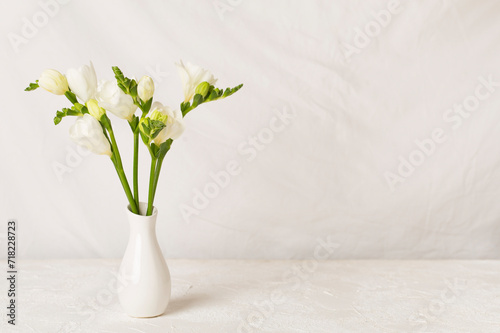 Nice bouquet of white freesia flowers in vase on table photo