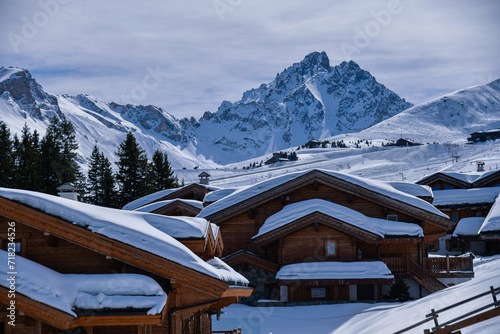 Fresh snow on the roofs of chalets in Courchevel, France. Amazing view of the mountains on the background.