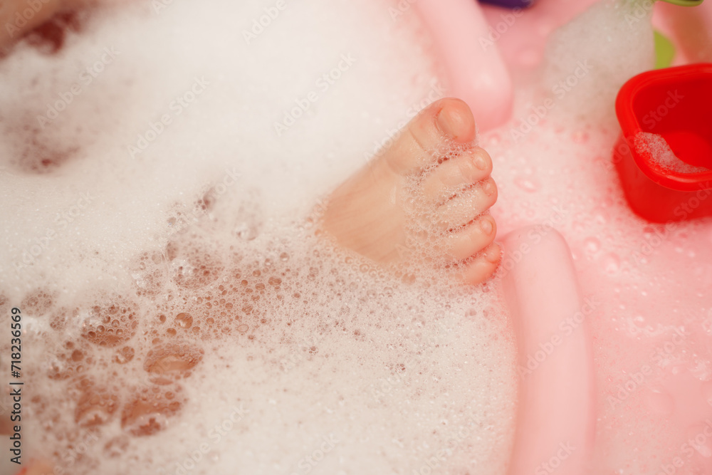 A cute baby's leg is bathed in foam in a bathtub