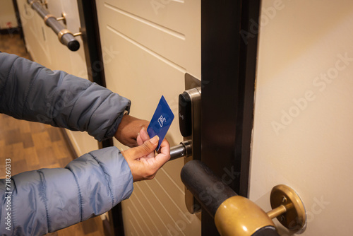 Closeup hand of young latin woman using a keycard to unlock electronic sensor of hotel door. Security concept. photo
