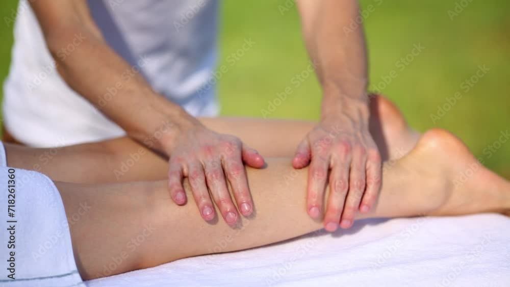 Masseur massaging the leg of a young woman outdoors Masseur massaging the leg of a young woman outdoors