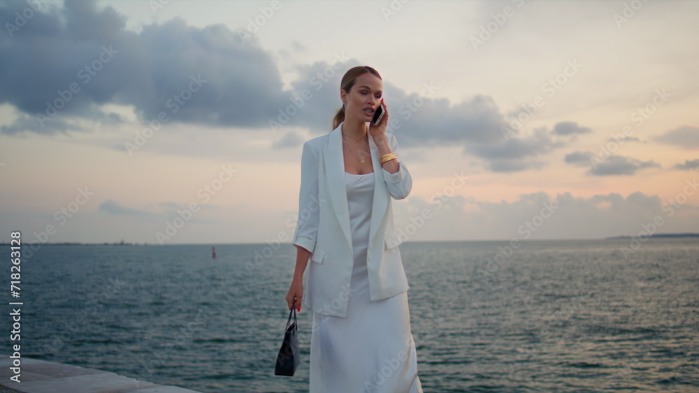 Elegant lady calling at sunset sky. Woman talking smartphone walking embankment Elegant lady calling at sunset sky. Woman talking smartphone walking embankment