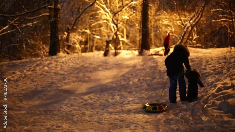 Back of unrecognizable woman and kid with snowtube in winter evening Back of unrecognizable woman and kid with snowtube in winter evening