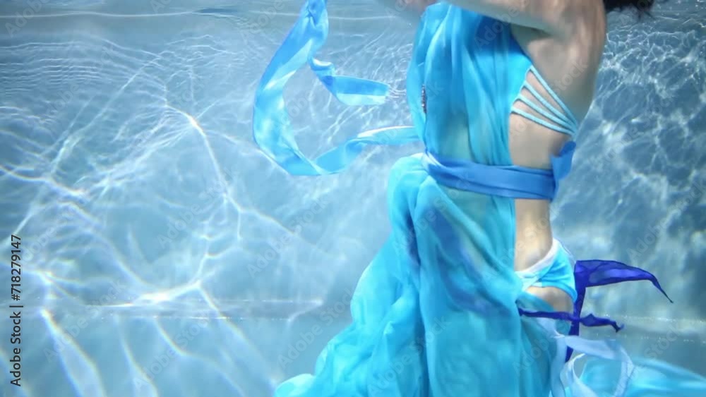 Beautiful young woman in blue swimwear is swimming at the pool, profile view. Beautiful young woman in blue swimwear is swimming at the pool, profile view.