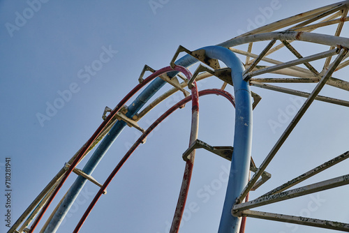 Red and Blue Roller Coaster Tracks Against Blue Sky, Upward View