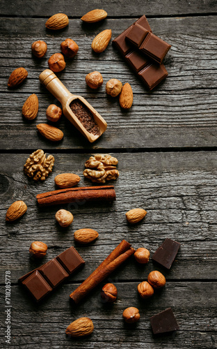 Chocolate, cinnamon, almonds, walnuts and hazelnuts on wood table. Verical background
