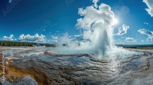  a geyser spewing out water into the air with a blue sky in the back ground and clouds in the back ground and a person standing on the other side of the geyser.