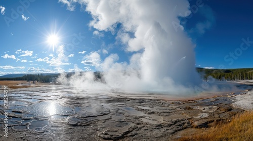  a geyser spewing water into the sky with a bright sun in the middle of the picture and a grassy area to the side of the water.