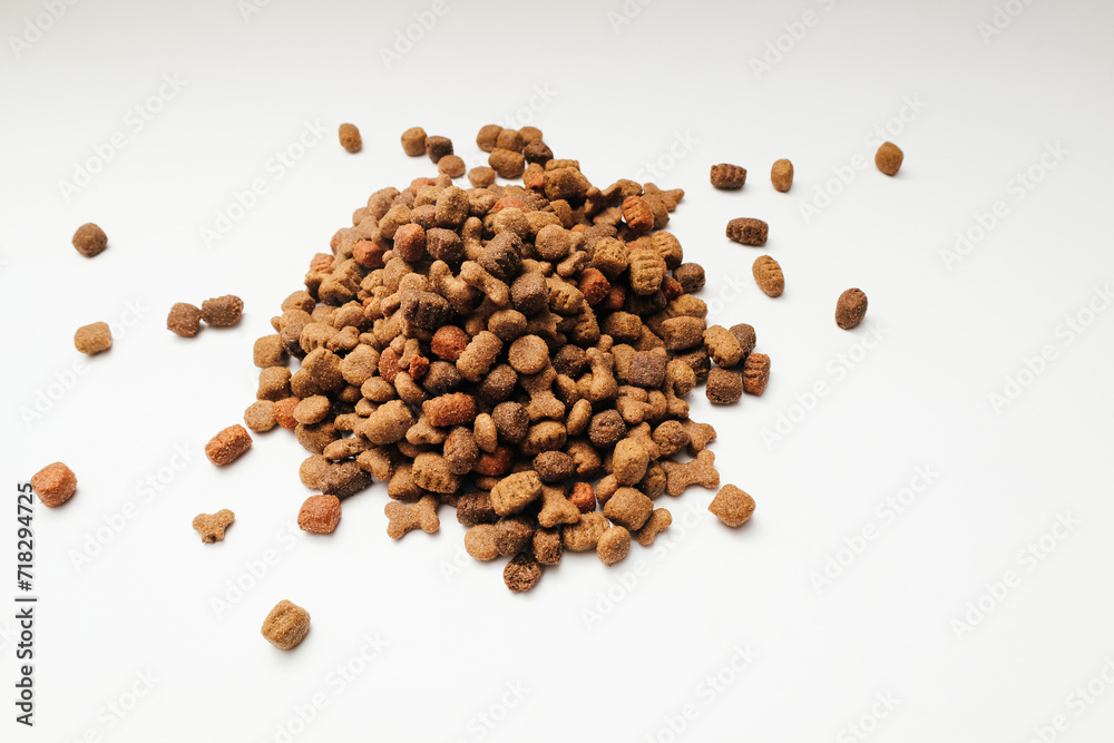 A slide of dry dog food on a white background. Heap of dry dog food on a white background. A slide of dry dog food on a white background. Heap of dry dog food on a white background.