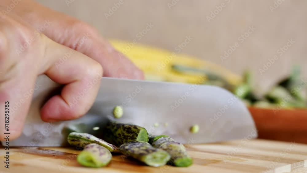 Detail: A woman chef uses a kitchen knife to cut green bean pods on a cutting board and place them on a plate. Vegetarian food and diet. Plant protein is becoming popular. Refusal of meat Detail: A woman chef uses a kitchen knife to cut green bean pods on a cutting board and place them on a plate. Vegetarian food and diet. Plant protein is becoming popular. Refusal of meat
