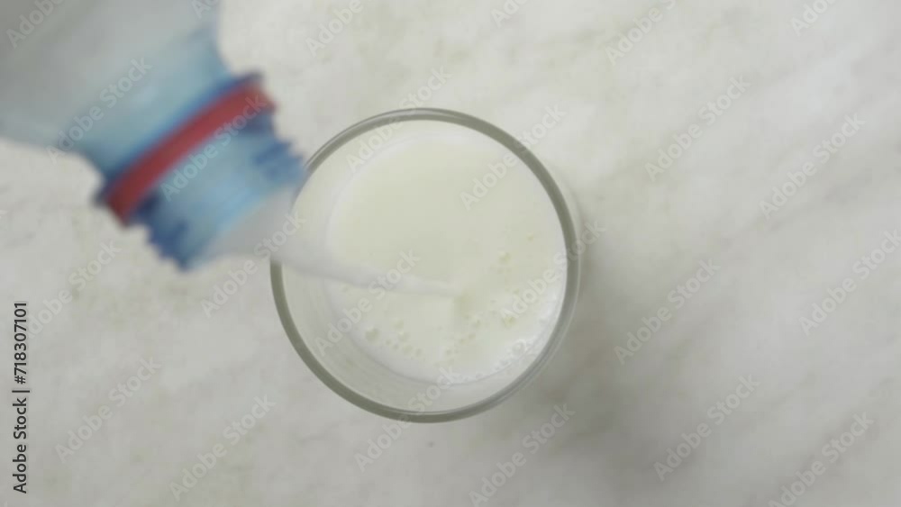 Milk is pouring from the bottle into glass of milk,top view Milk is pouring from the bottle into glass of milk,top view