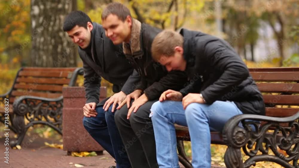 Three young men stand up from the bench in autumn park Three young men stand up from the bench in autumn park