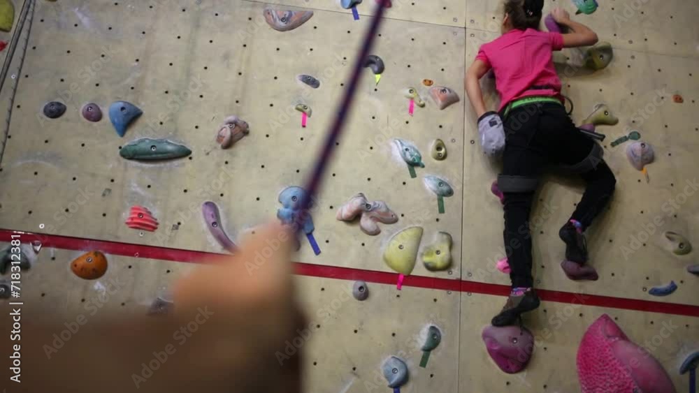 Girl on climbing wall reaches into bag of chalk. Girl on climbing wall reaches into bag of chalk.