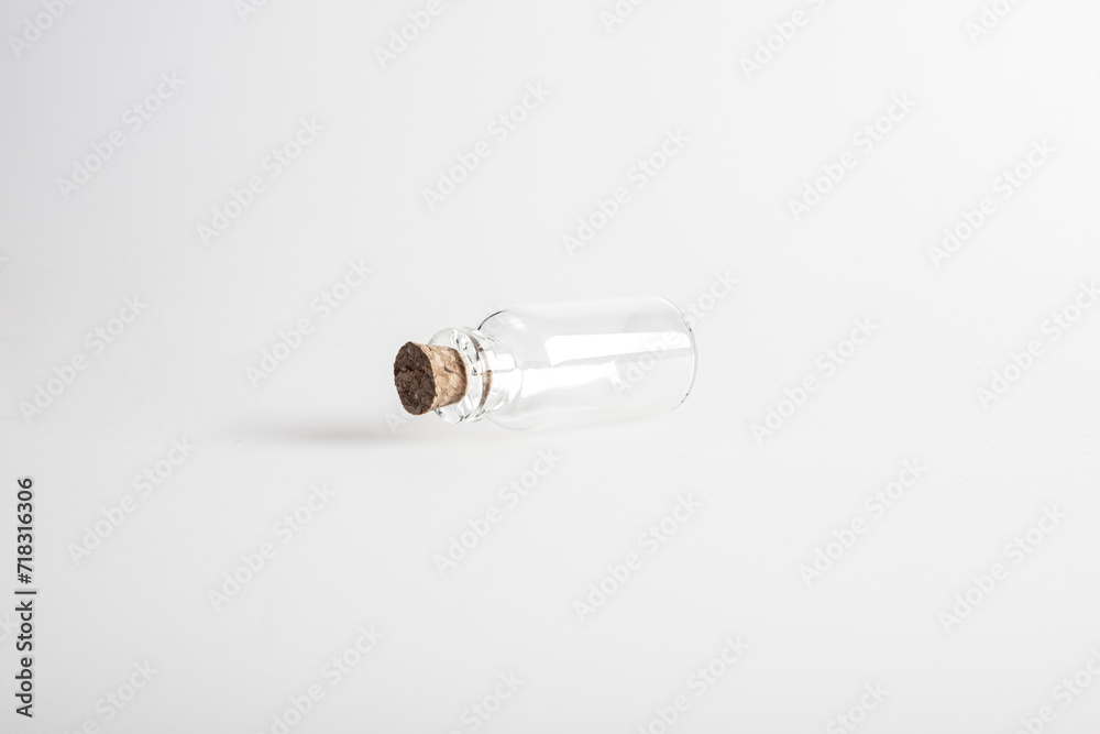 One empty mini glas bottle with closed brown cork lid laying down. The rustic and vintage jar is small and clean. It looks like an old medicin keeping. One empty mini glas bottle with closed brown cork lid laying down. The rustic and vintage jar is small and clean. It looks like an old medicin keeping.