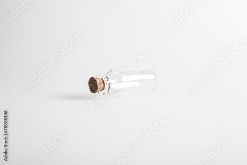 One empty mini glas bottle with closed brown cork lid laying down. The rustic and vintage jar is small and clean. It looks like an old medicin keeping. 