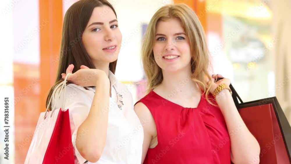 Two girls sit in shopping center, consider buying. Focus on left woman Two girls sit in shopping center, consider buying. Focus on left woman