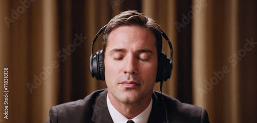 ritratto primo piano di giovane uomo concentrato con occhi chiusi che ascolta musica in cuffia photo
