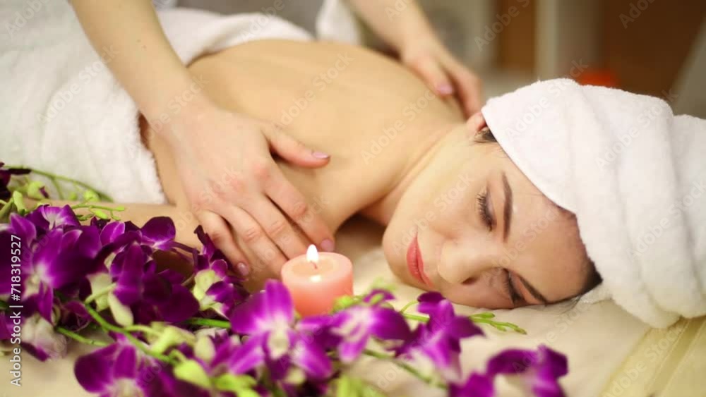 Masseuse making massage in circular movements of woman lying in flowers Masseuse making massage in circular movements of woman lying in flowers