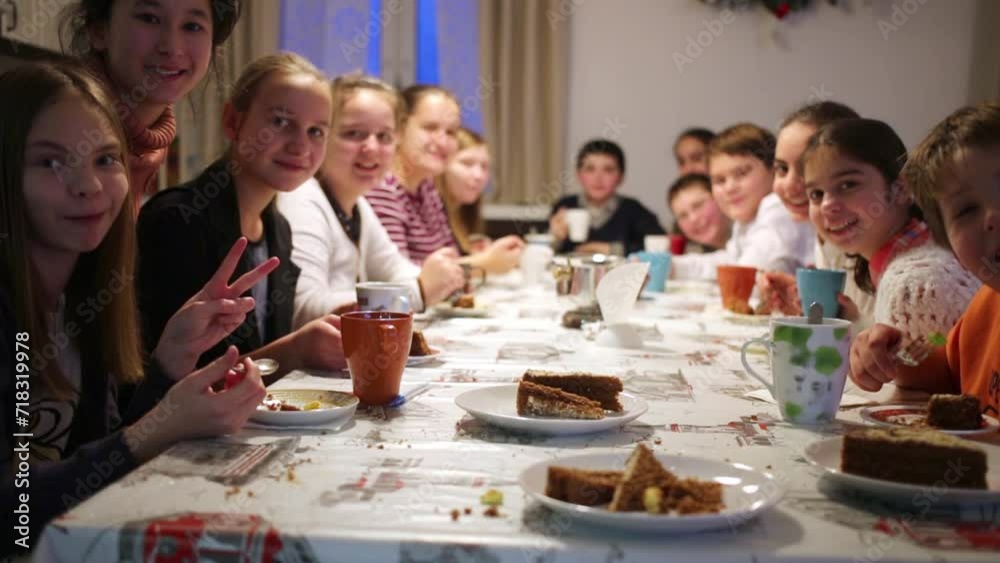 Group of thirteen children sits at table during tea party. Group of thirteen children sits at table during tea party.