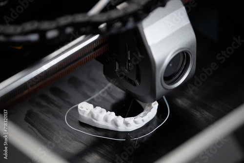 Macro shot of 3D printer extruder producing white-colored human lower jaw bone sample in engineering laboratory photo