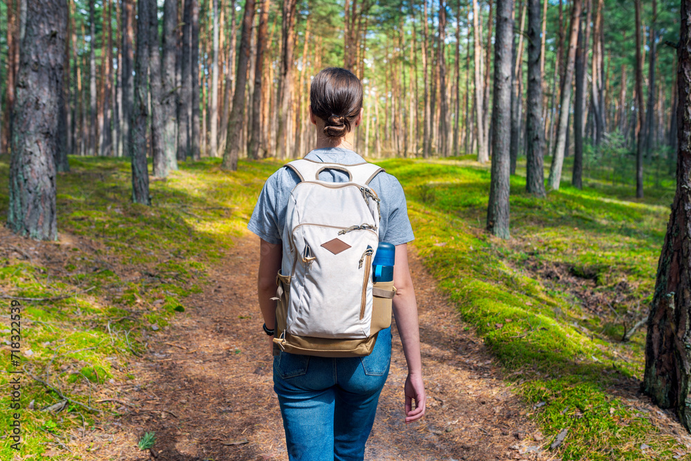 A young woman with a backpack walks through the forest. Hiking in the woods. A young woman with a backpack walks through the forest. Hiking in the woods.