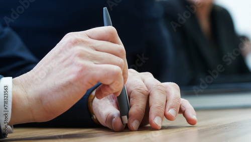 Man holds a fountain pen with his fingers while sitting at his desk during a business meeting. Anonymous, unrecognizable, no face.  Photo. Selective focus photo