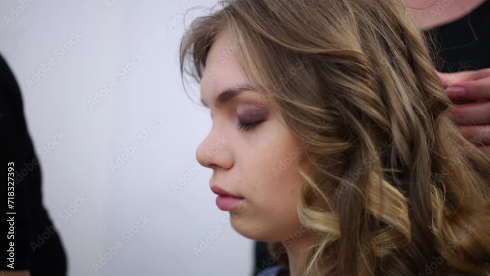 A hairdresser makes hair style with long curly hair A hairdresser makes hair style with long curly hair