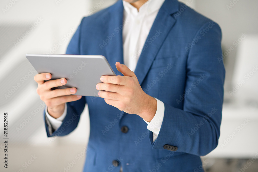 Cropped shot of businessman is engaged with a tablet, his fingers skillfully navigating device, highlighting the importance of digital proficiency in modern business. The essence of a dynamic workday Cropped shot of businessman is engaged with a tablet, his fingers skillfully navigating device, highlighting the importance of digital proficiency in modern business. The essence of a dynamic workday