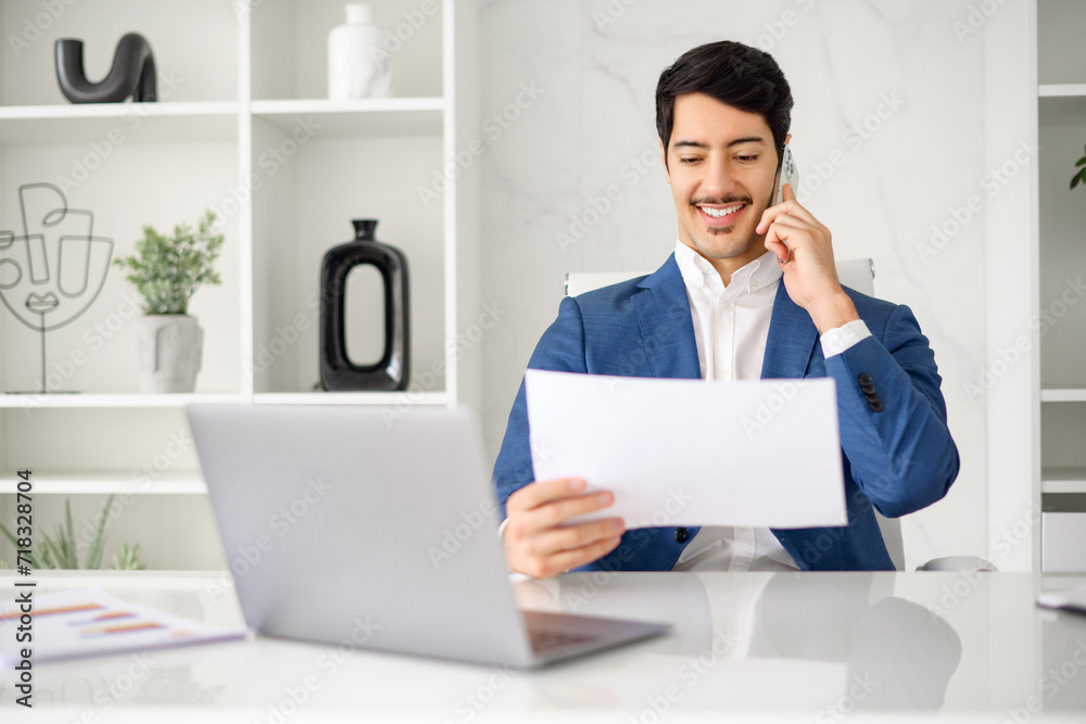 Hispanic businessman attentively examines a document while on a phone call, capturing the multitasking nature of the business environment, male office employee talking while looking through contract Hispanic businessman attentively examines a document while on a phone call, capturing the multitasking nature of the business environment, male office employee talking while looking through contract