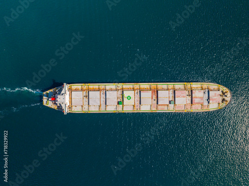 A large container cargo ship travels over calm, blue ocean