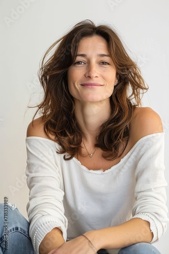 Happy woman sitting against white background at studio