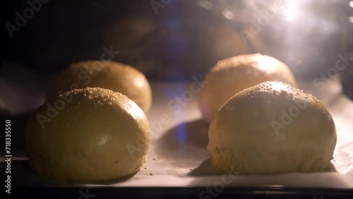 Timelapse of burger buns with sesame seeds baking in the hot oven. The process of baking four delicious burger buns as they rise and turn golden brown. Homemade bakery concept. High quality 4k footage