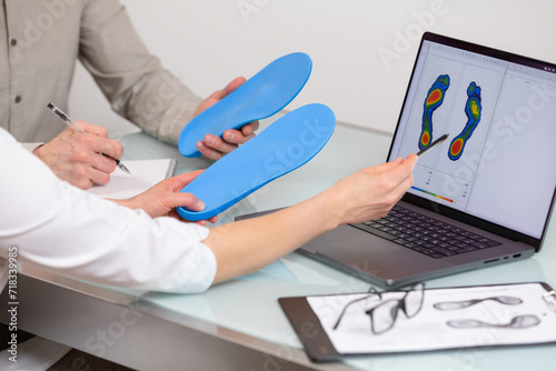 Doctor consulting patient on custom orthotic insoles in a clinic for a personalised custom fit. Feet recreation medicine concept photo
